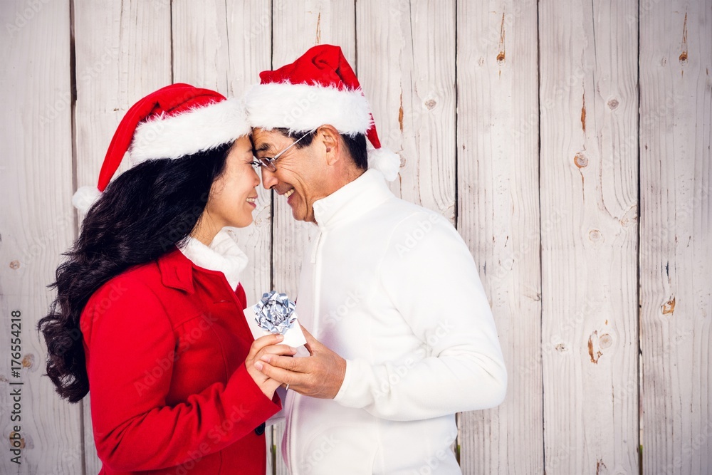 Composite image of festive senior couple exchanging gifts