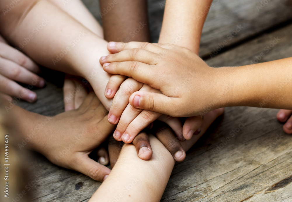 Diverse hands are join together on the wooden table