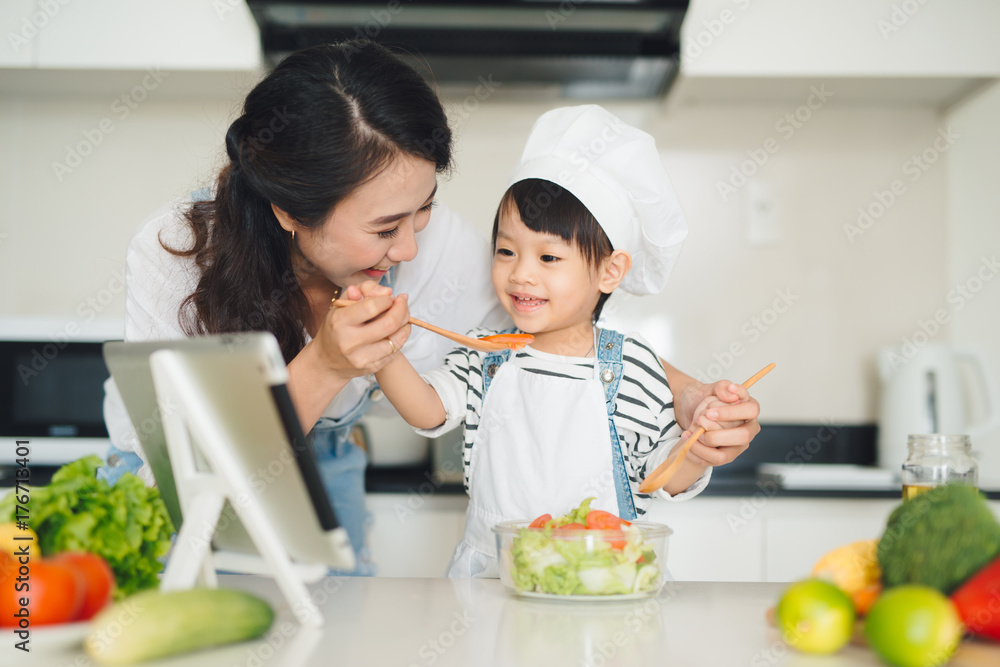 Mother with her daughter in the kitchen cooking together