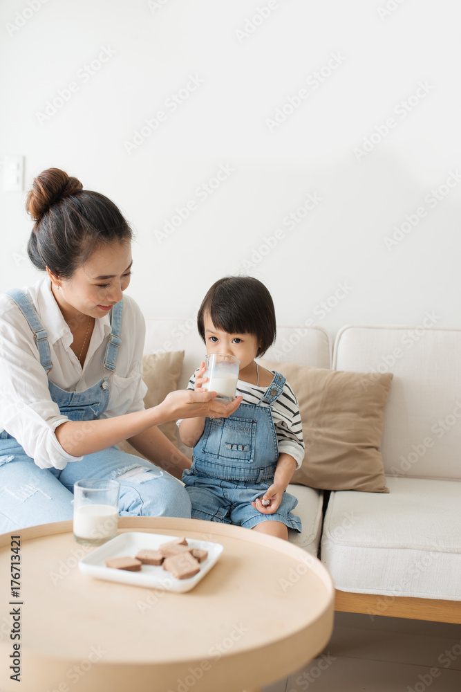 Happy family of asian mom is drinking milk with her cute daughter in the morning at home