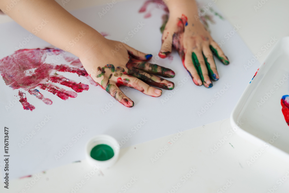 Little asian girl painting with paintbrush and colorful paints