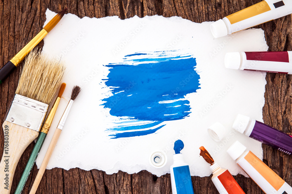 Art brush and blue watercolor painted with white paper art  on wooden background