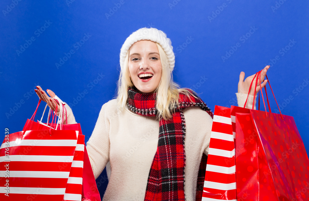 Happy young woman holding shopping bags on a solid background