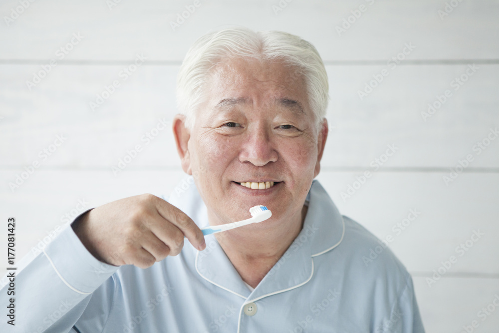 An elderly man is brushing his teeth