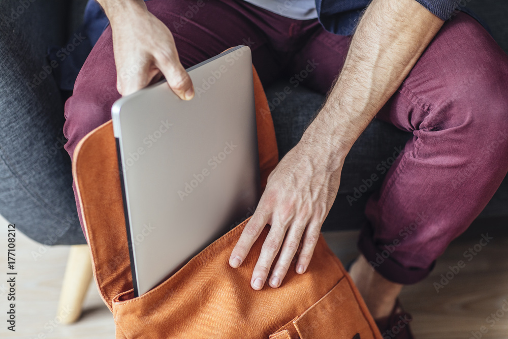 Man Putting Laptop in Backpack