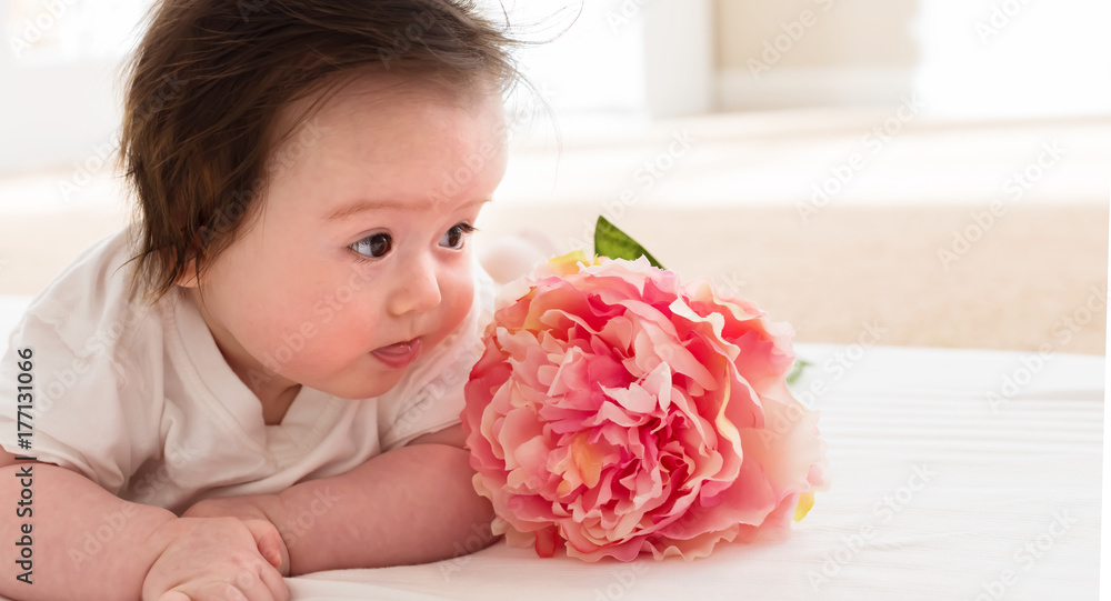 Happy baby boy with a pink flower