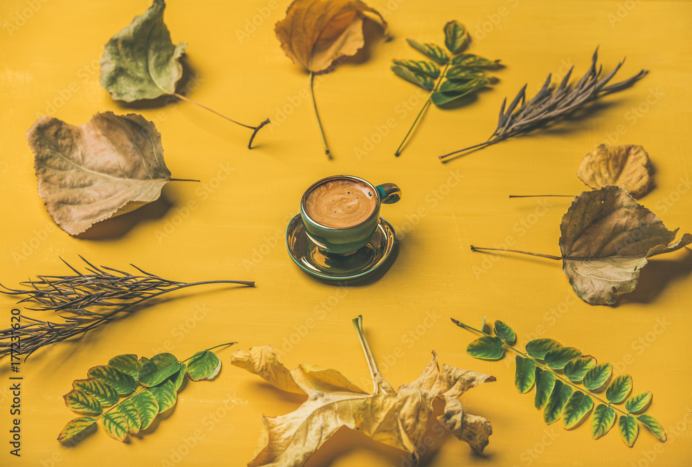 Fall coffee concept. Flat-lay of espresso cup surrounded by dried yellow and green tree leaves over 