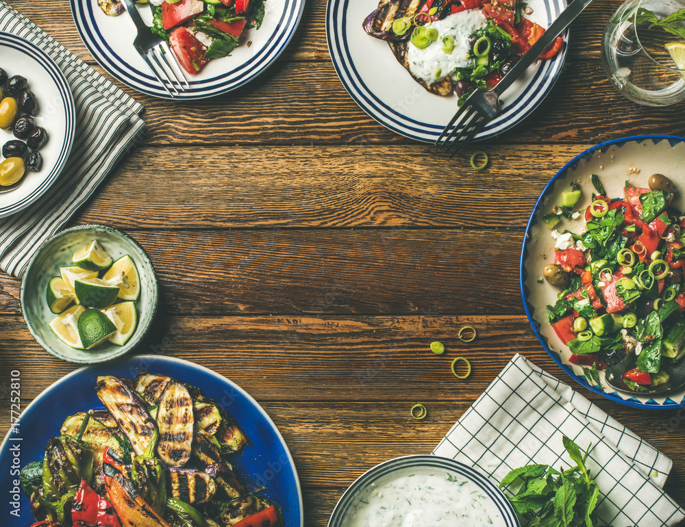 Flat-lay of healthy dinner table setting. Fresh salad, grilled vegetables with yogurt and dill sauce