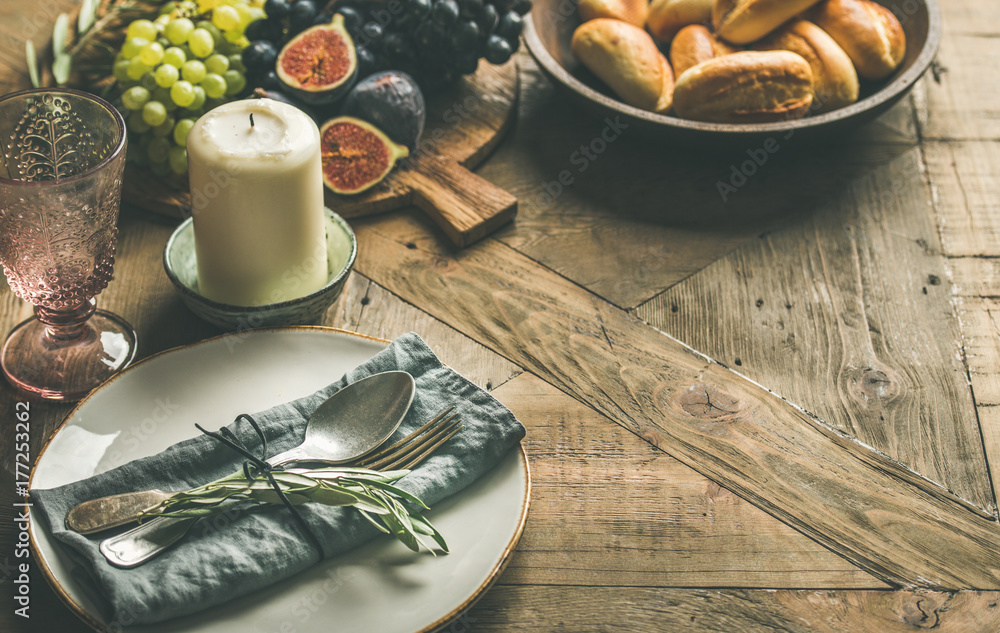 Fall holiday table decoration setting. Plate with napkin, fork, spoon, glass, candle, grapes and fig