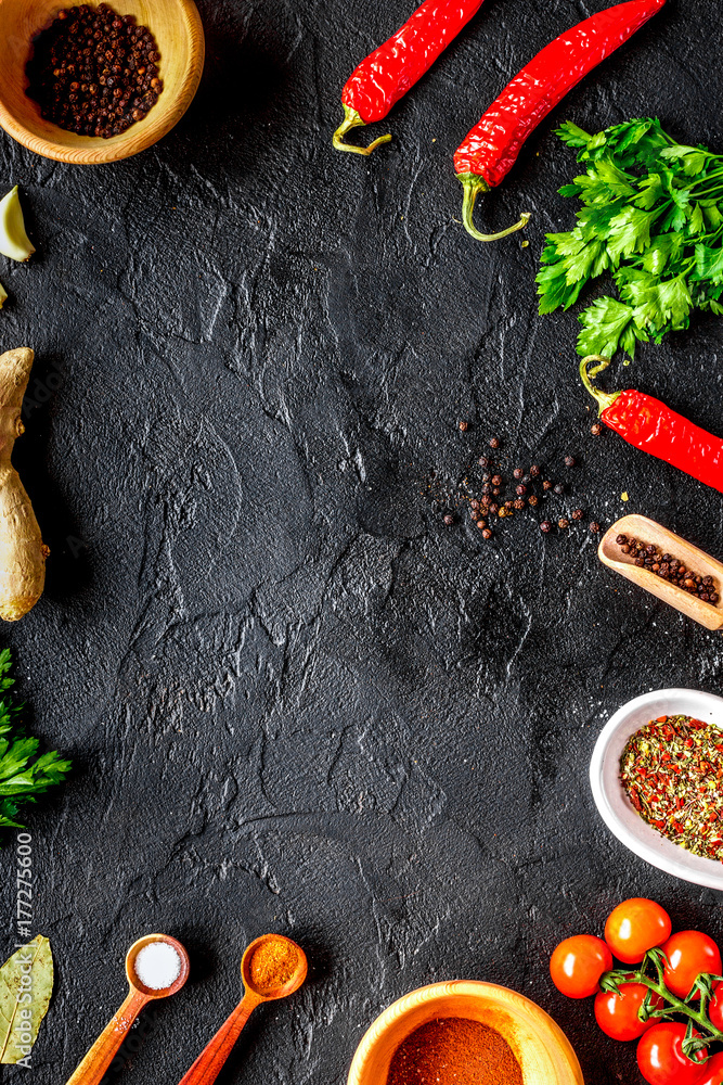 spices in wooden spoon on dark background top view