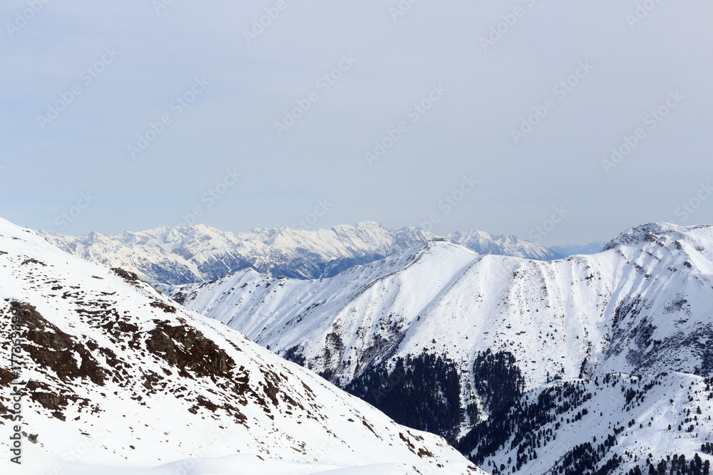 奥地利斯塔拜阿尔卑斯山冬季有雪、树和蓝天的山脉全景