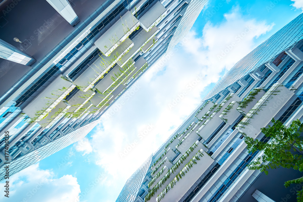 Low angle perspective view of modern office building with green eco concept balcony .