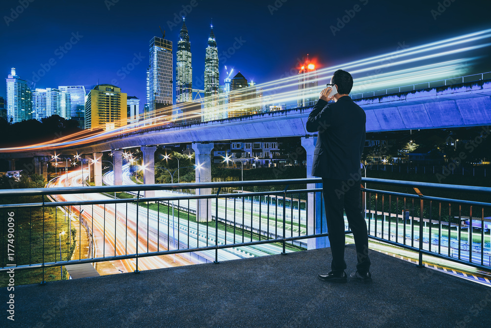 商人在露天露台上打电话，市中心有红绿灯的现代城市