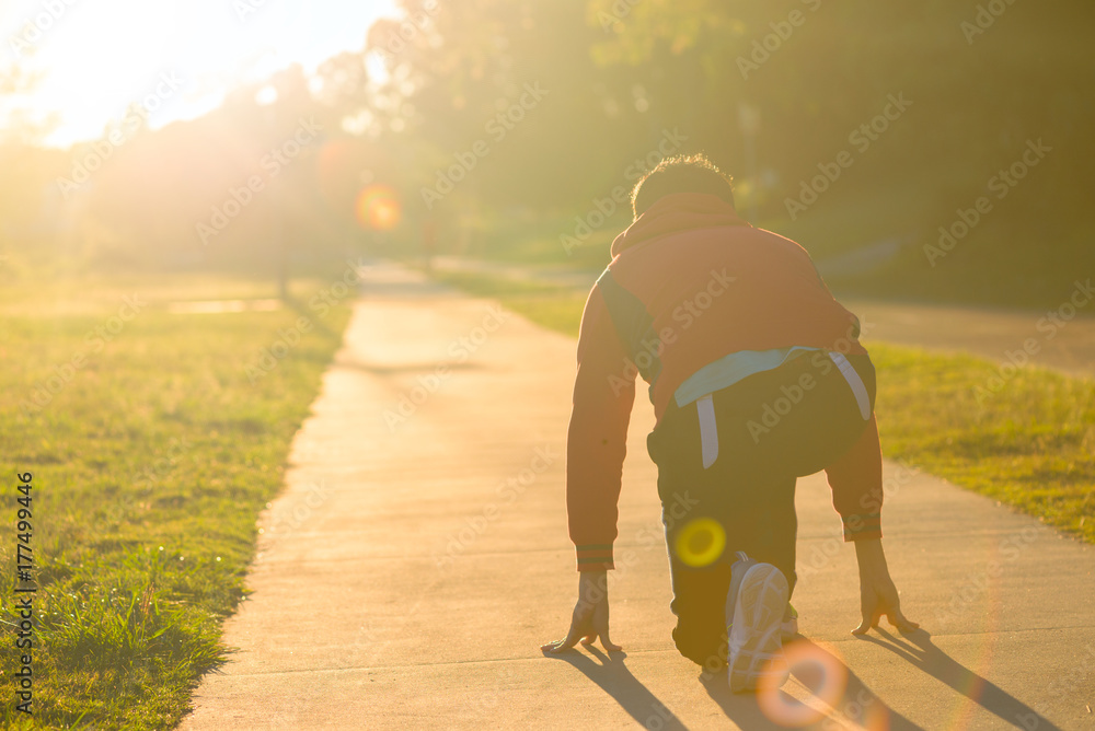 An athlete man is starting to run in the park with his gold and target.