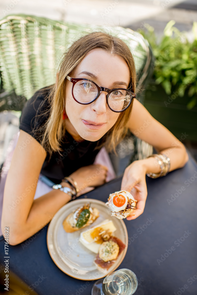 一位年轻的女士正在享用美味的开胃菜，配以传统的西班牙小吃和一杯葡萄酒。