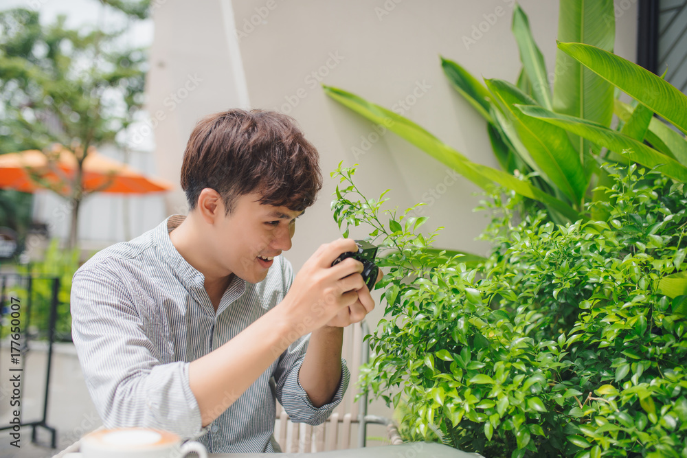 年轻摄影师坐在咖啡馆的桌子旁拍照