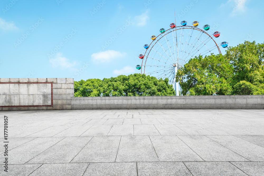 Empty floor square and playground ferris wheel in the city park