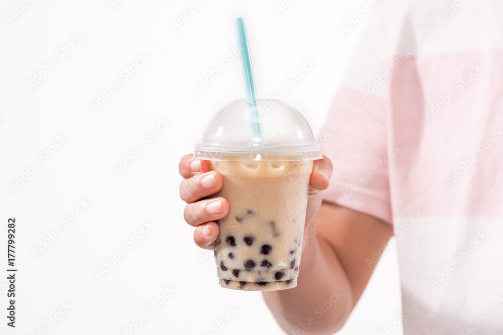 在桌子上的塑料杯里喝浅棕色奶油泡泡茶和黑色木薯珍珠。