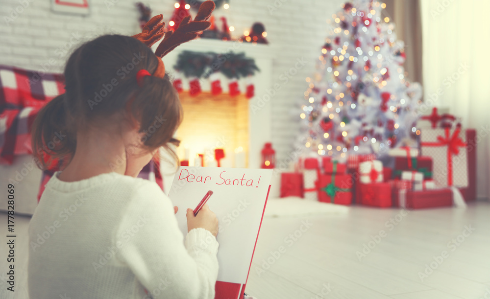 child girl writing letter santa home near Christmas tree