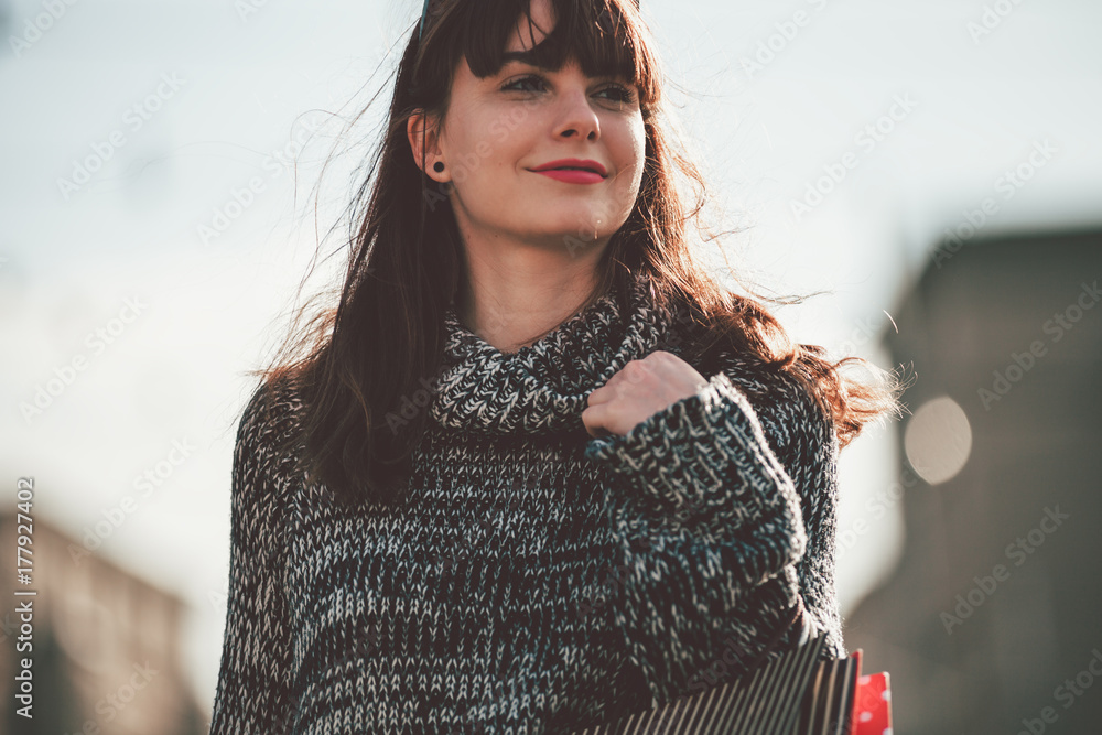 Woman with shopping bags walking on street, city scene