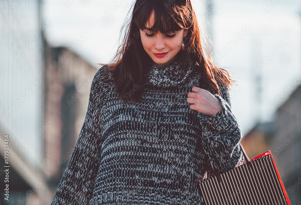 Woman with shopping bags walking on street, city scene