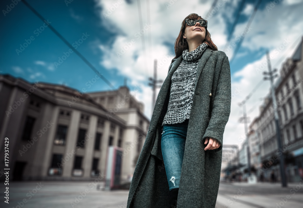 休闲时尚都市场景，穿着外套的时髦女人走在街上