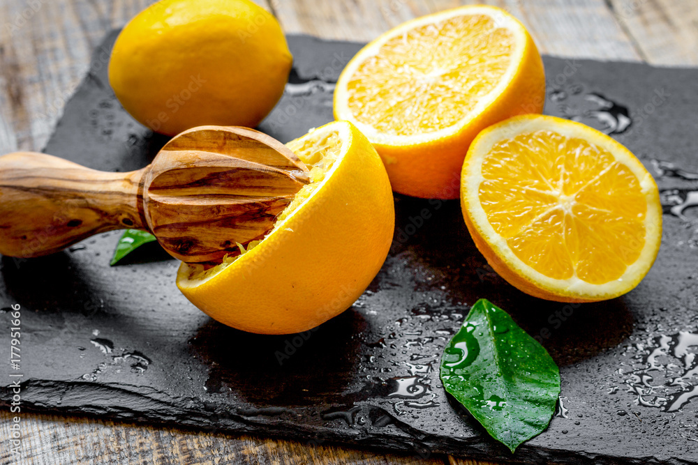 cut oranges in half and juicer on wooden background