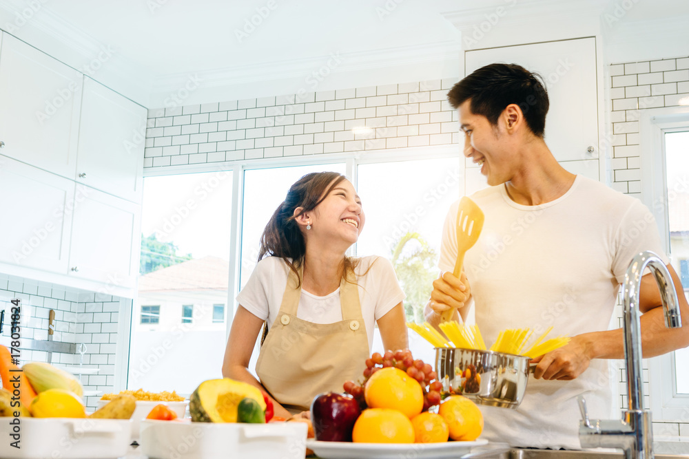 一对亚洲青少年夫妇正在帮忙做晚饭。他们一起快乐地做面包。在美国的情人节