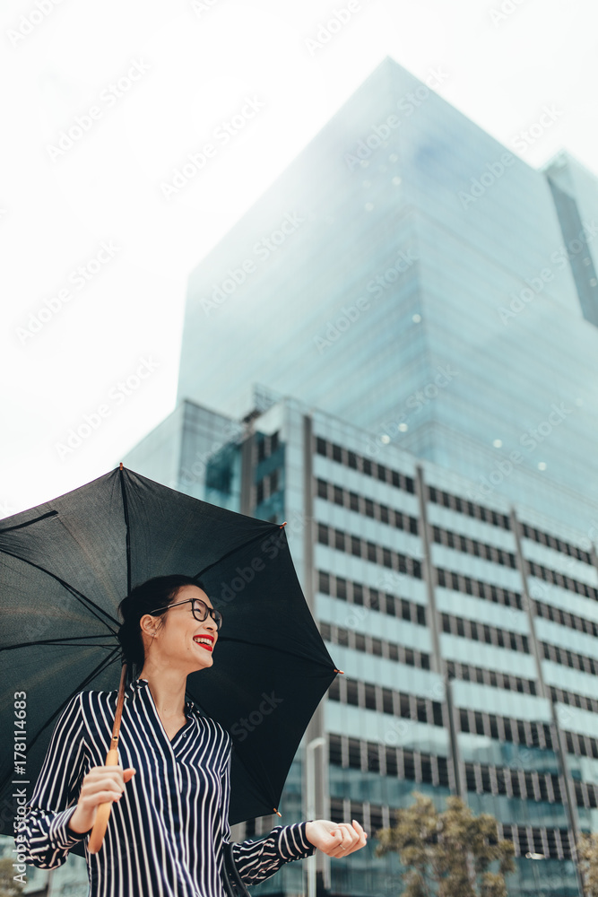 带着雨伞在城市户外微笑的女人