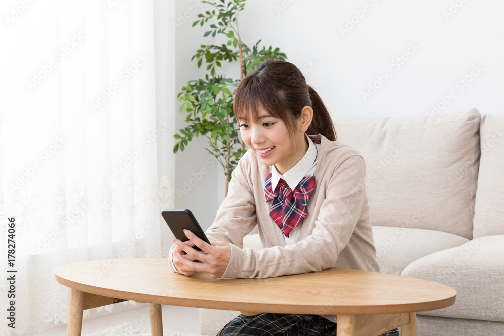 リビングでスマートフォンを使う女子高生