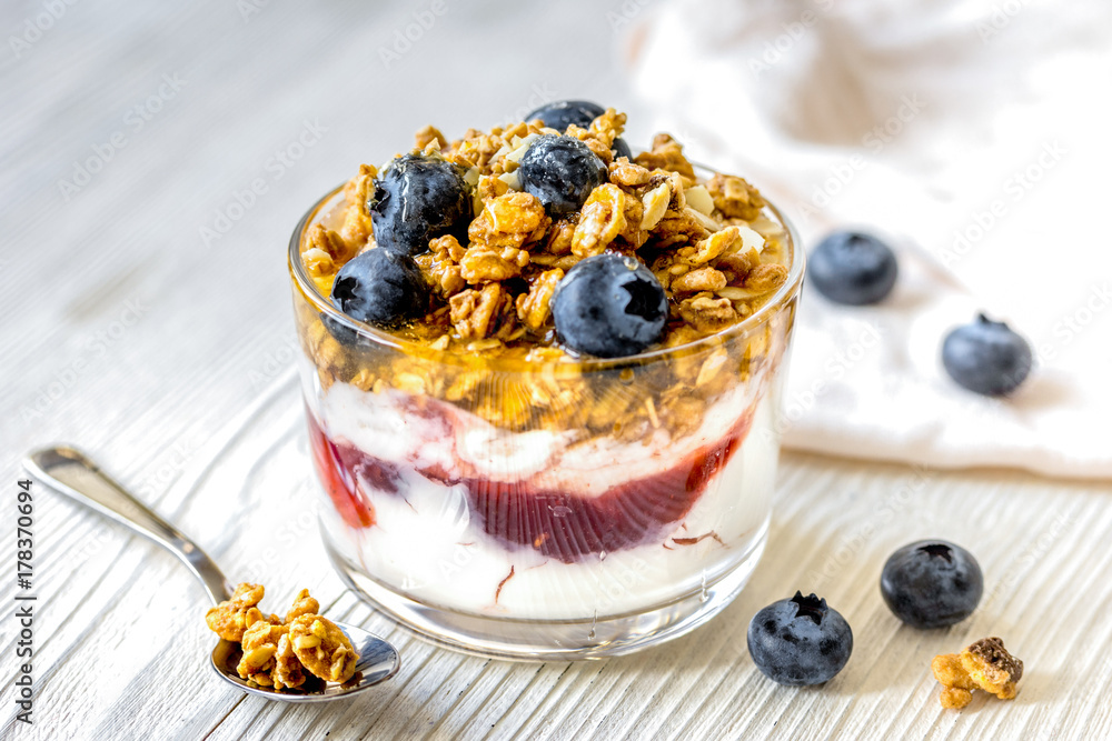 Morning granola with yogurt and berries on white kitchen backgro