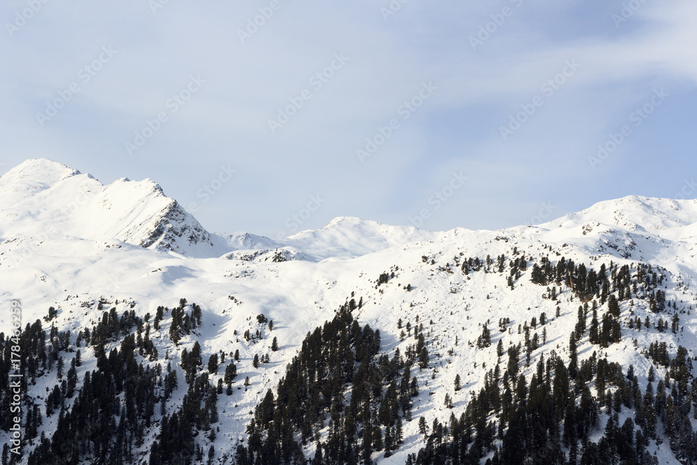 奥地利斯塔拜阿尔卑斯山冬季有雪、树和蓝天的山脉全景