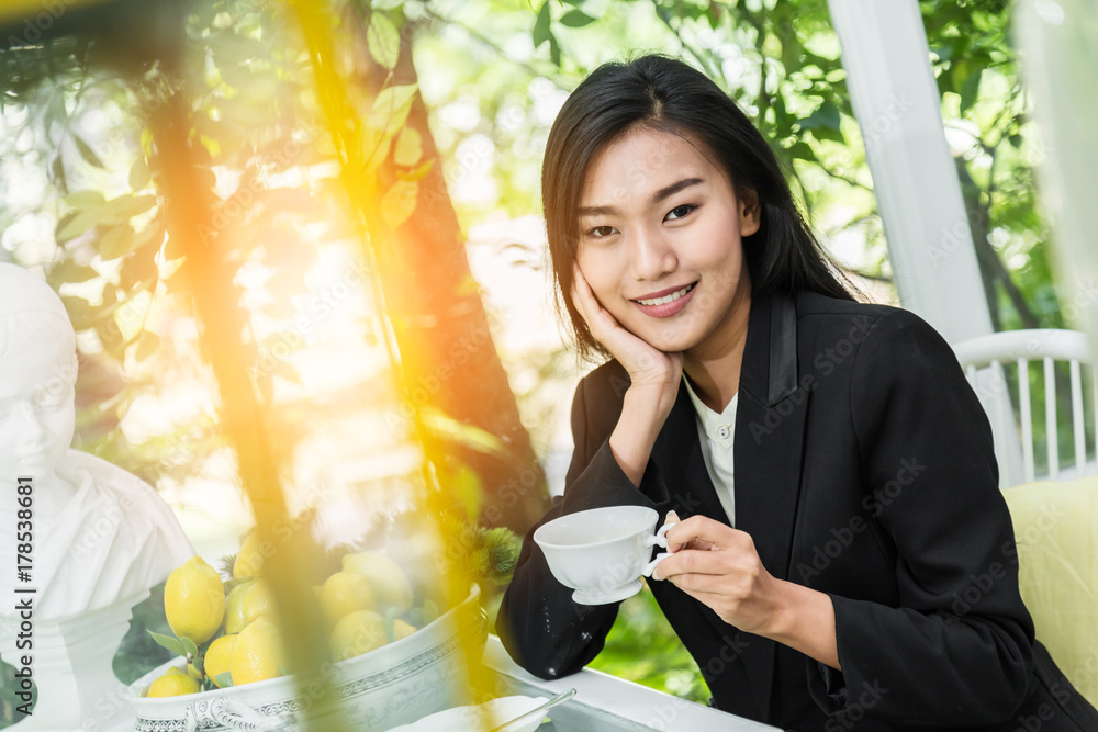 微笑的年轻女人在家里端着一杯绿茶，健康的生活方式理念，亚洲美女，亚洲b