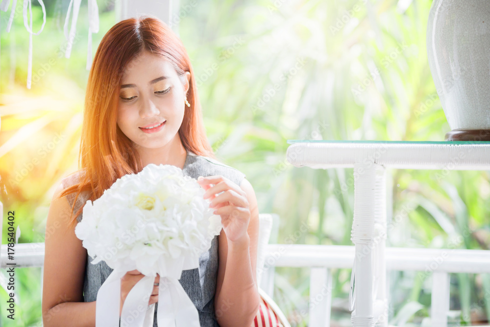 asian beautiful woman with white flower in white gazebo with garden background