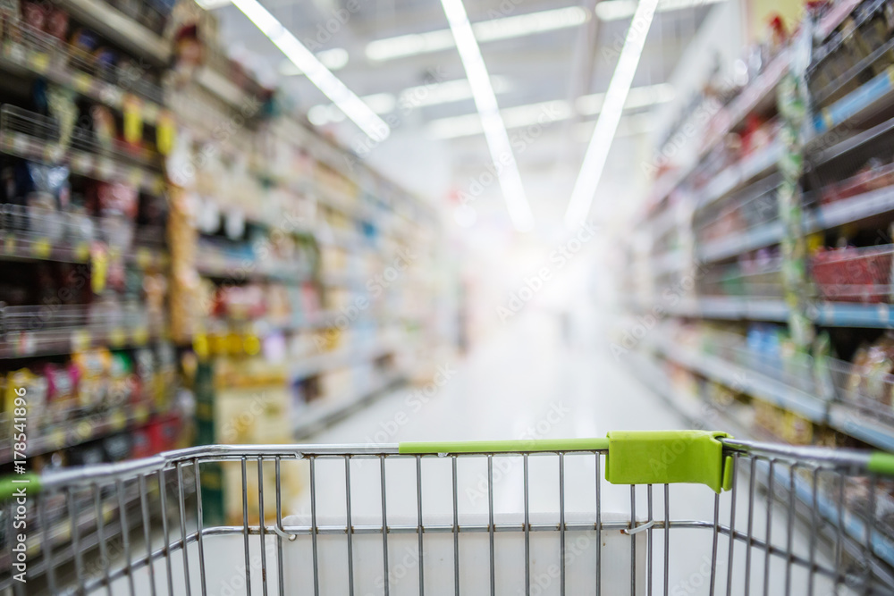 Supermarket aisle with empty green shopping cart after black Friday.