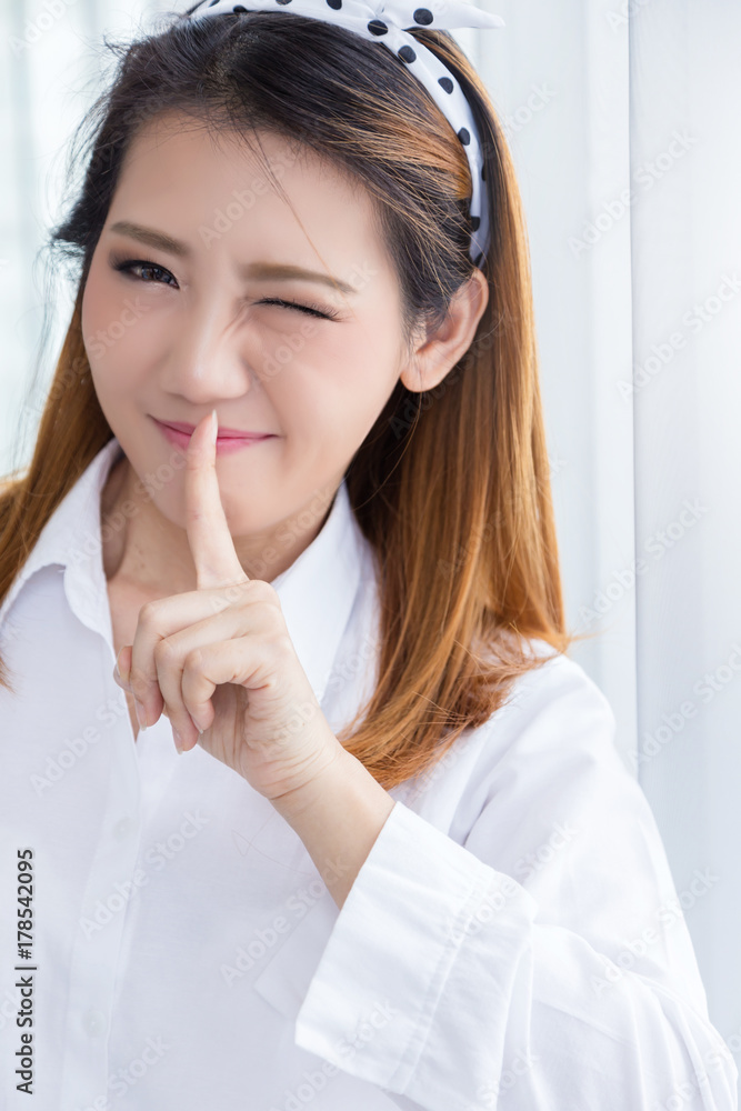 Young beautiful asian woman silence  using her hands as sign  with white curtain background