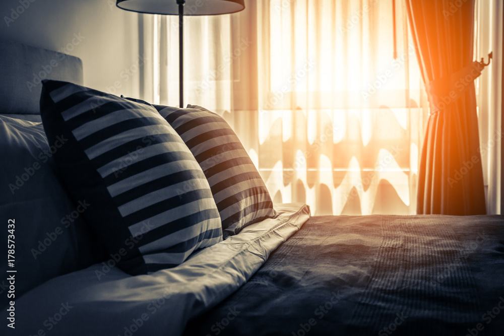 Bed maid-up with clean white pillows and bed sheets in beauty room. Close-up. Lens flair in sunlight