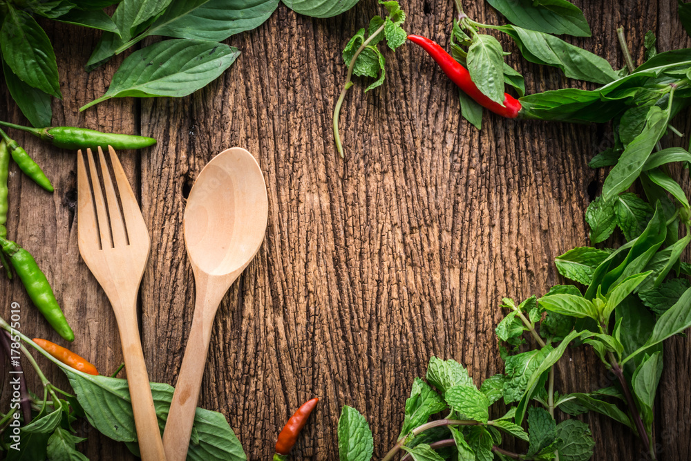 wooden spoon with chili and basil asian herb and in gredients on old vintage wooden texture backgrou