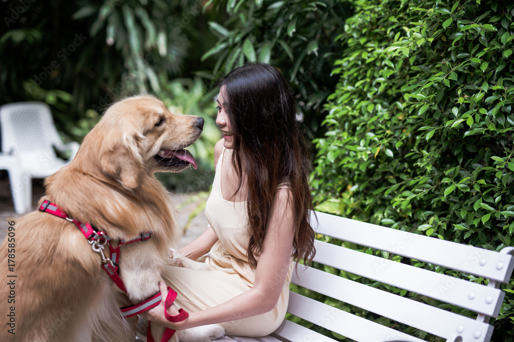 带着狗金毛寻回犬的女人在公园里的肖像，日落在门外