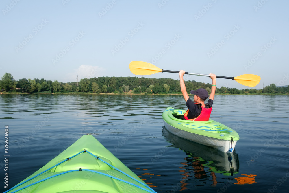 Boy in life jacket on green kayak