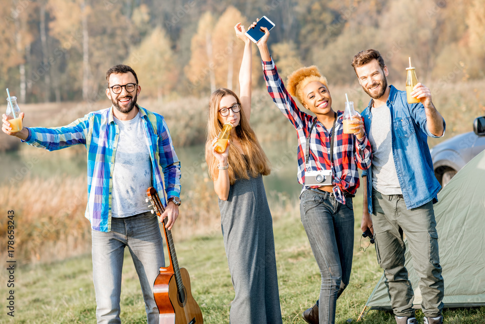 Multi ethnic group of friends dressed casually having fun dancing with drinks during the outdoor rec