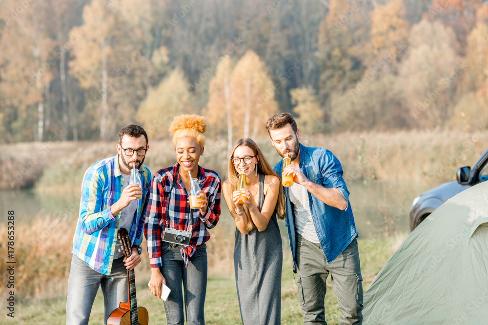 Multi ethnic group of friends dressed casually having fun with drinks during the outdoor recreation 