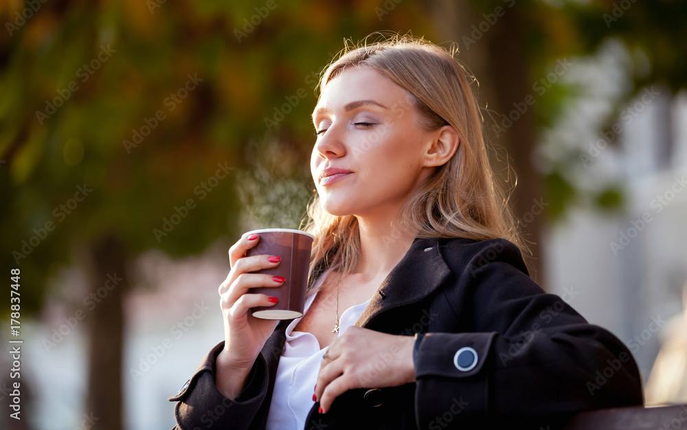 闻着热咖啡的女人，街上的秋日日落