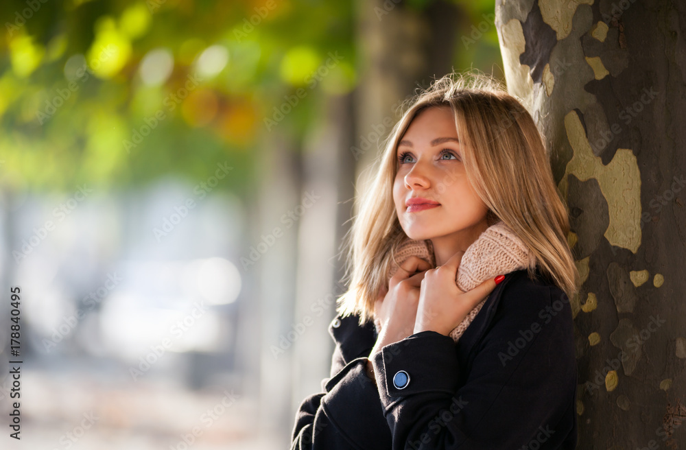 Woman under colorful autumn leaves during walk in the city