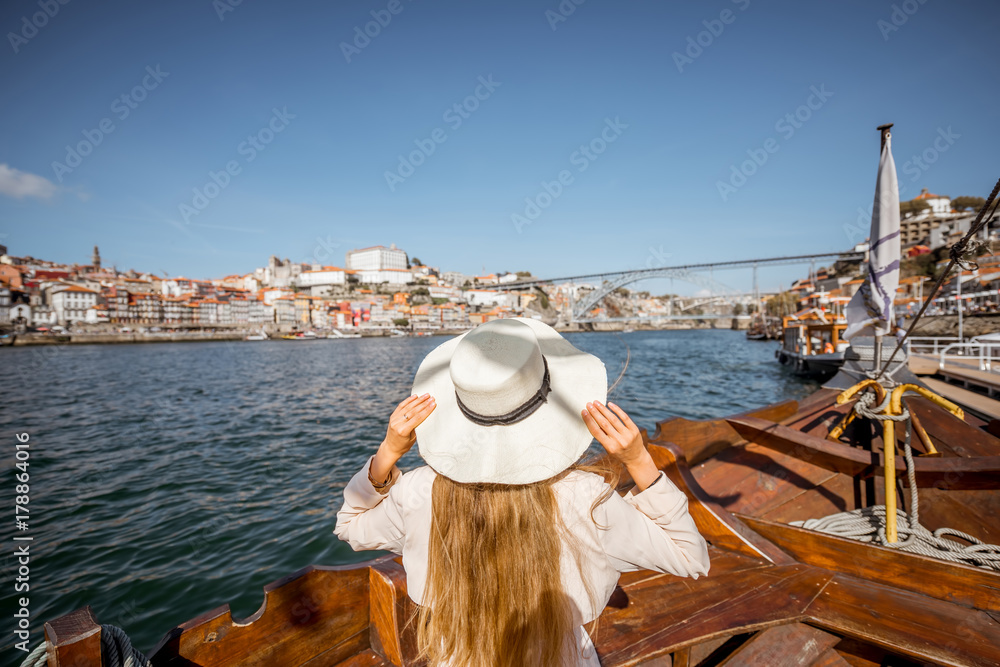 Young woman tourist standing back on the boat on Douro river in Porto city, Portugal