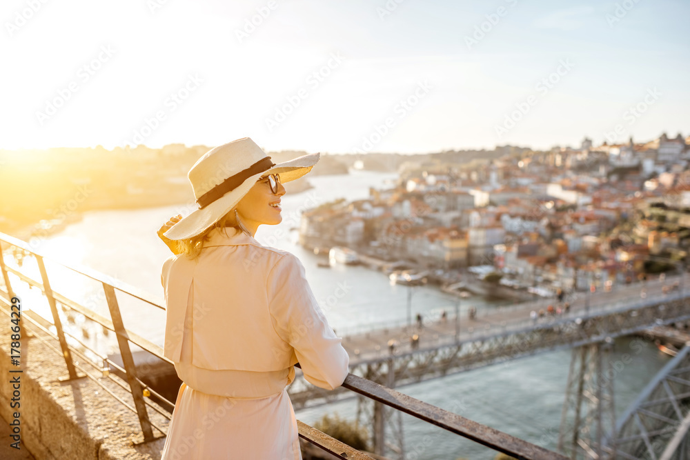 Young woman tourist enjoying beautiful aerial cityscape view with famous bridge during the sunset in