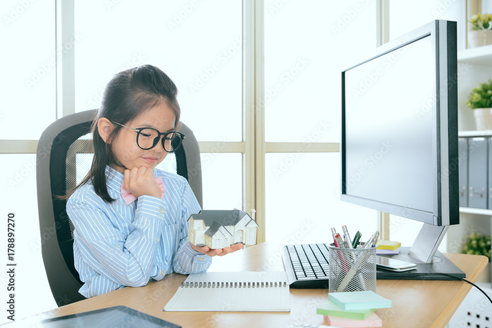 pretty little business girl looking at house model