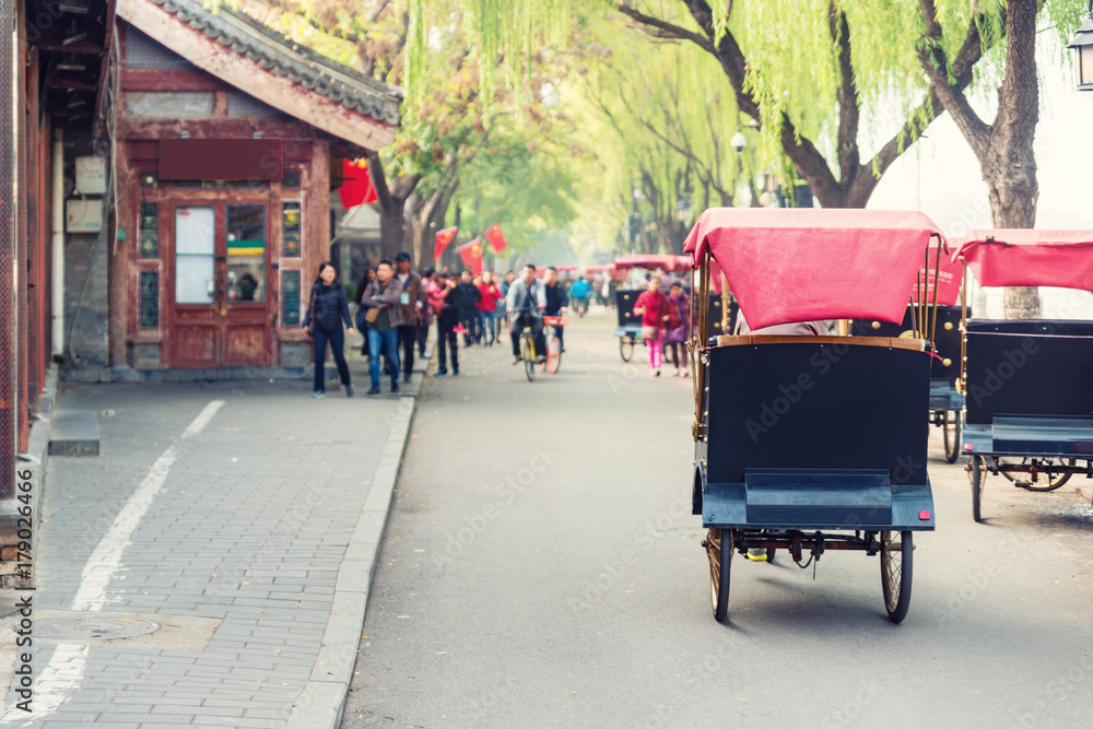 中国北京老胡同里骑着北京传统人力车的游客。