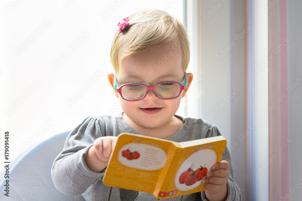 Little girl reading book at home