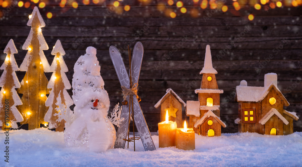 Christmas background with illuminated wooden village and snowman